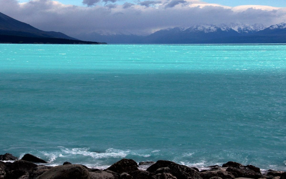 The glacier-blue water of Lake Pukaki beneath cloud-covered Southern Alps