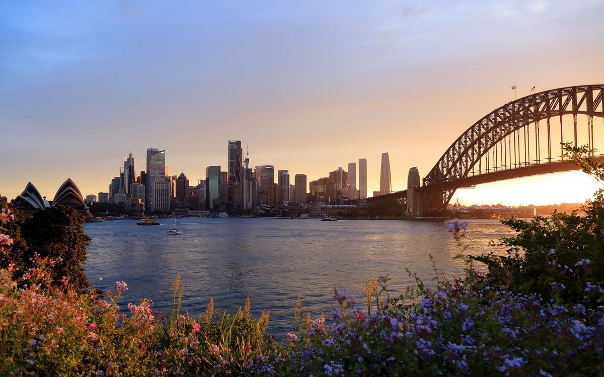 Sydney Opera House and Harbour Bridge across the water at sunset